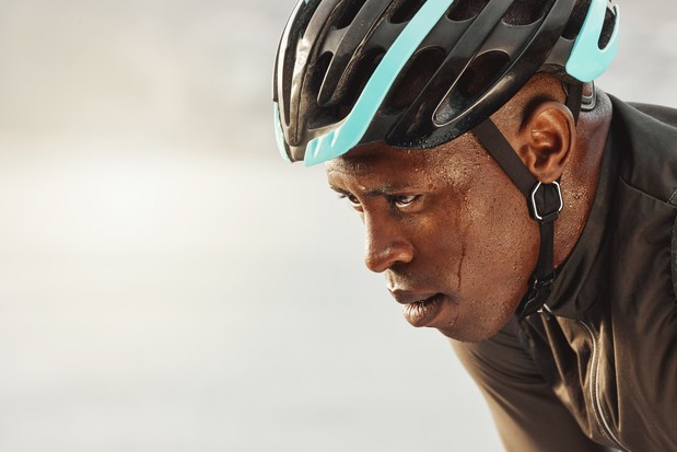 Homme cycliste, transpirant et se concentrant sur la course de marathon, la compétition ou l'événement sportif sur la maquette du ciel pour l'espace publicitaire ou le marketing.  Sportif à vélo dans un casque fatigué pour un défi de remise en forme