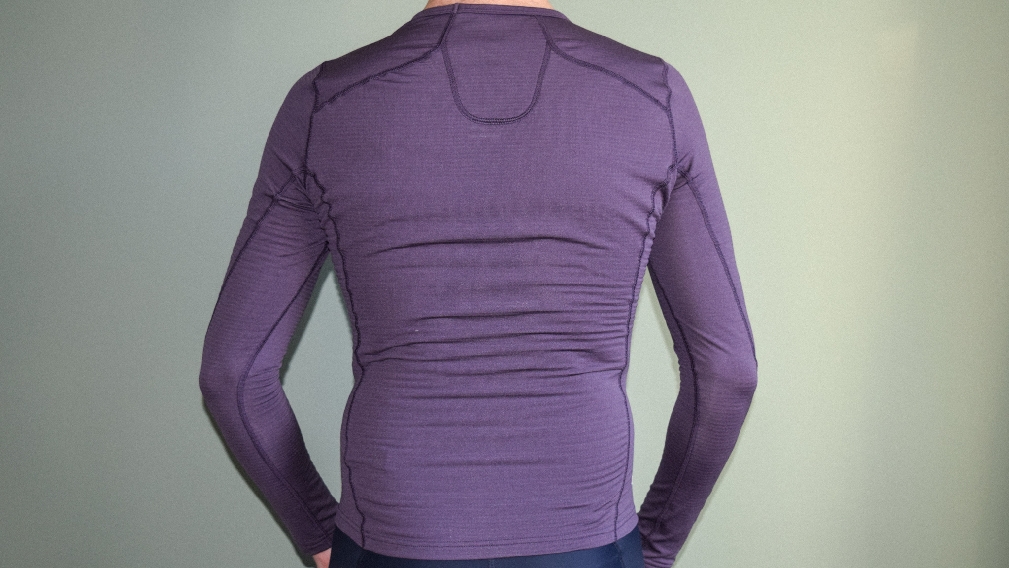 Une couche de base violette Maap Thermal LS vue de derrière portée par un homme.  Les coutures traversent les épaules et autour de la nuque