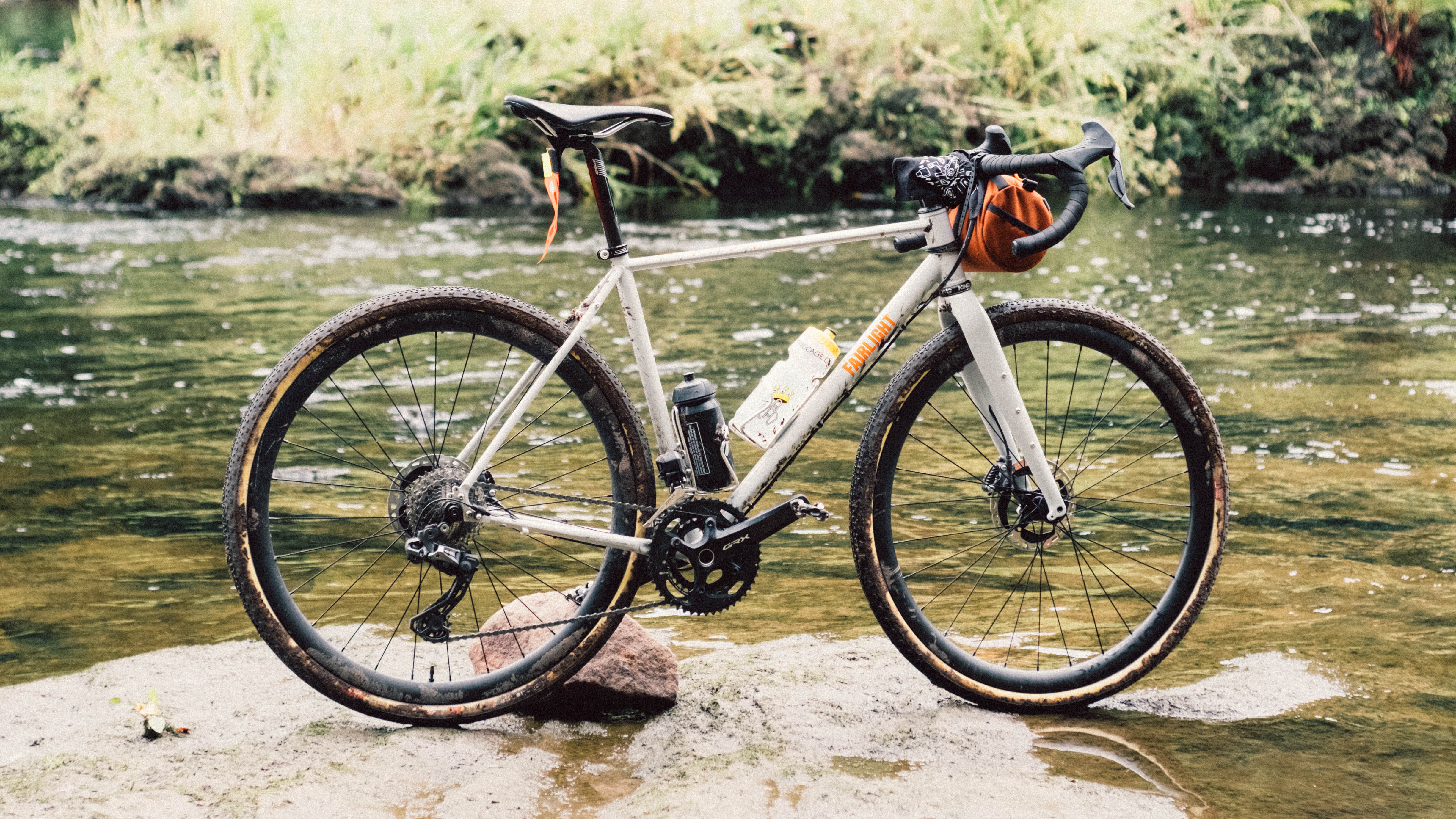 Un vélo blanc se dresse à côté d'une rivière