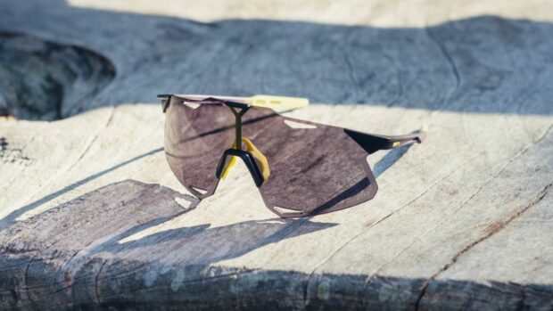 A pair of 100% Hypercraft cycling glasses on a wooden bench