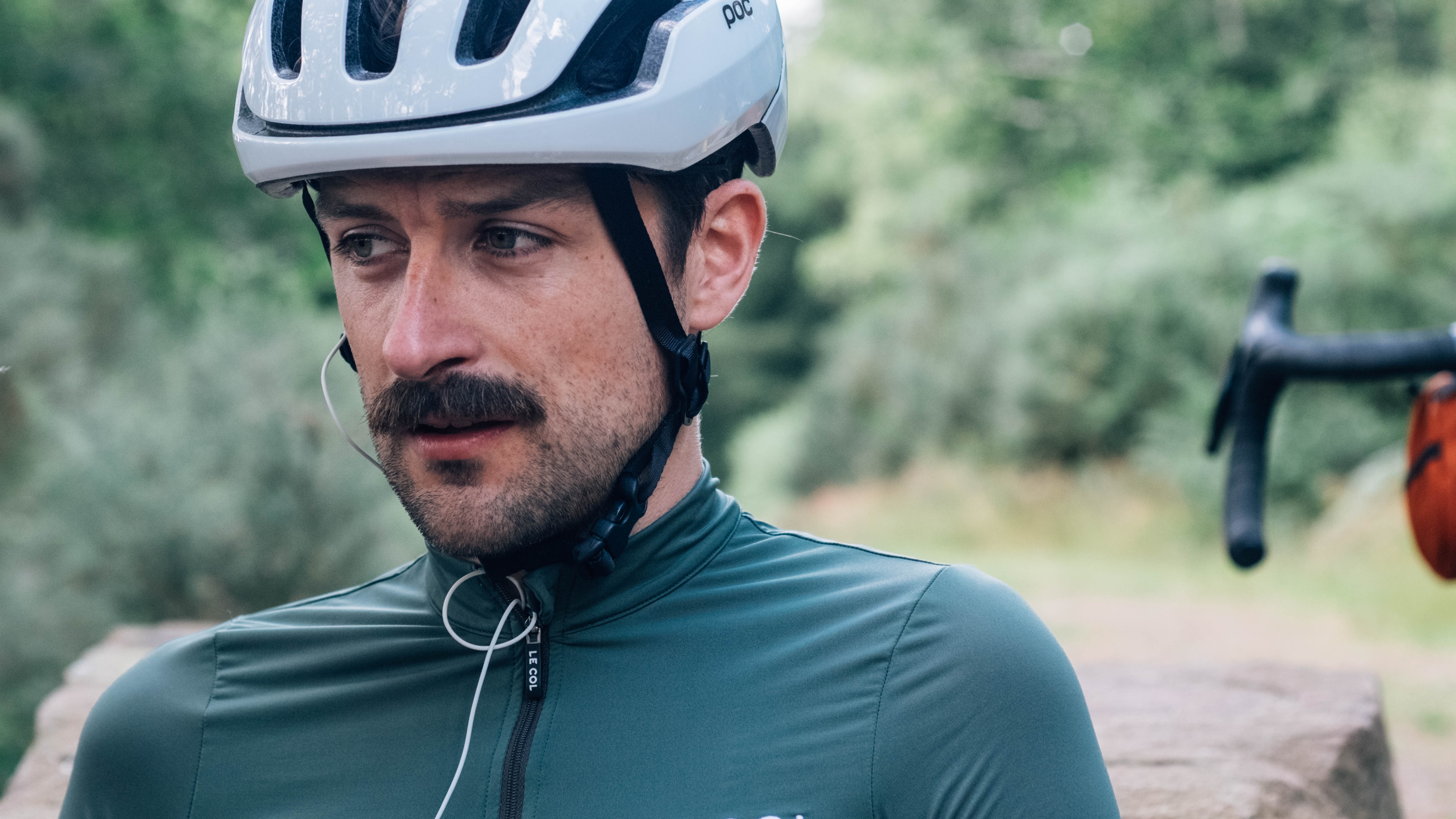 Un homme blanc avec une moustache porte le maillot vert sauge le col pro II