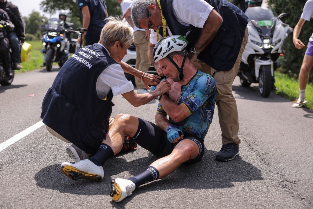 Medics treat Mark Cavendish on the roadside after he crashed during stage 8 at the Tour de France