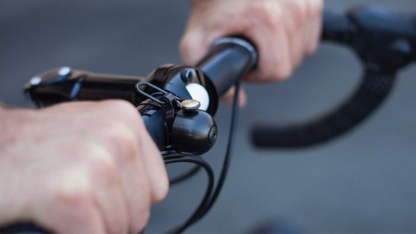 Two hands gripping the flats of a drop bar with a black Spurcycle bell in the middle