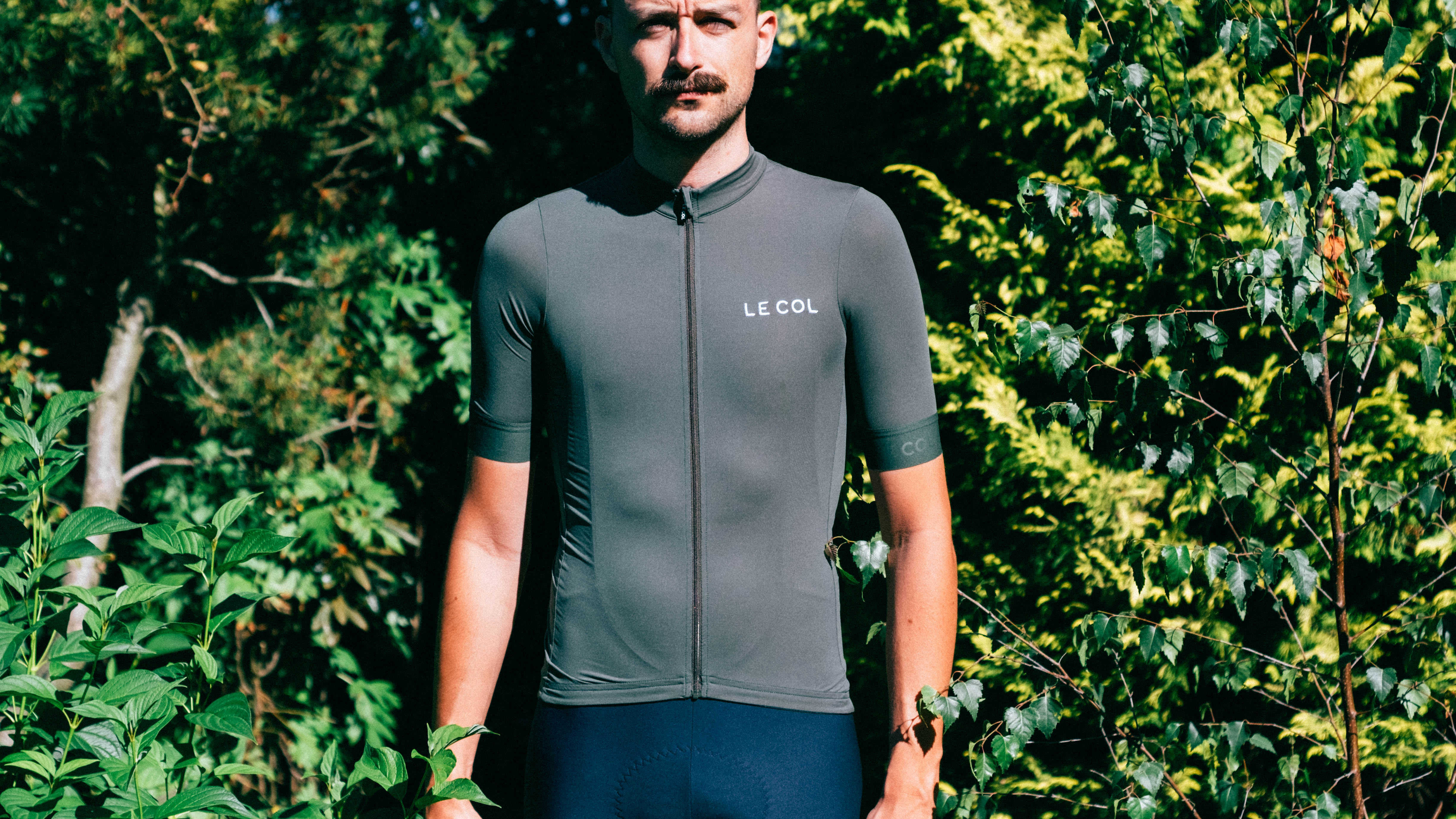 Un homme blanc avec une moustache porte le maillot vert sauge le col pro II