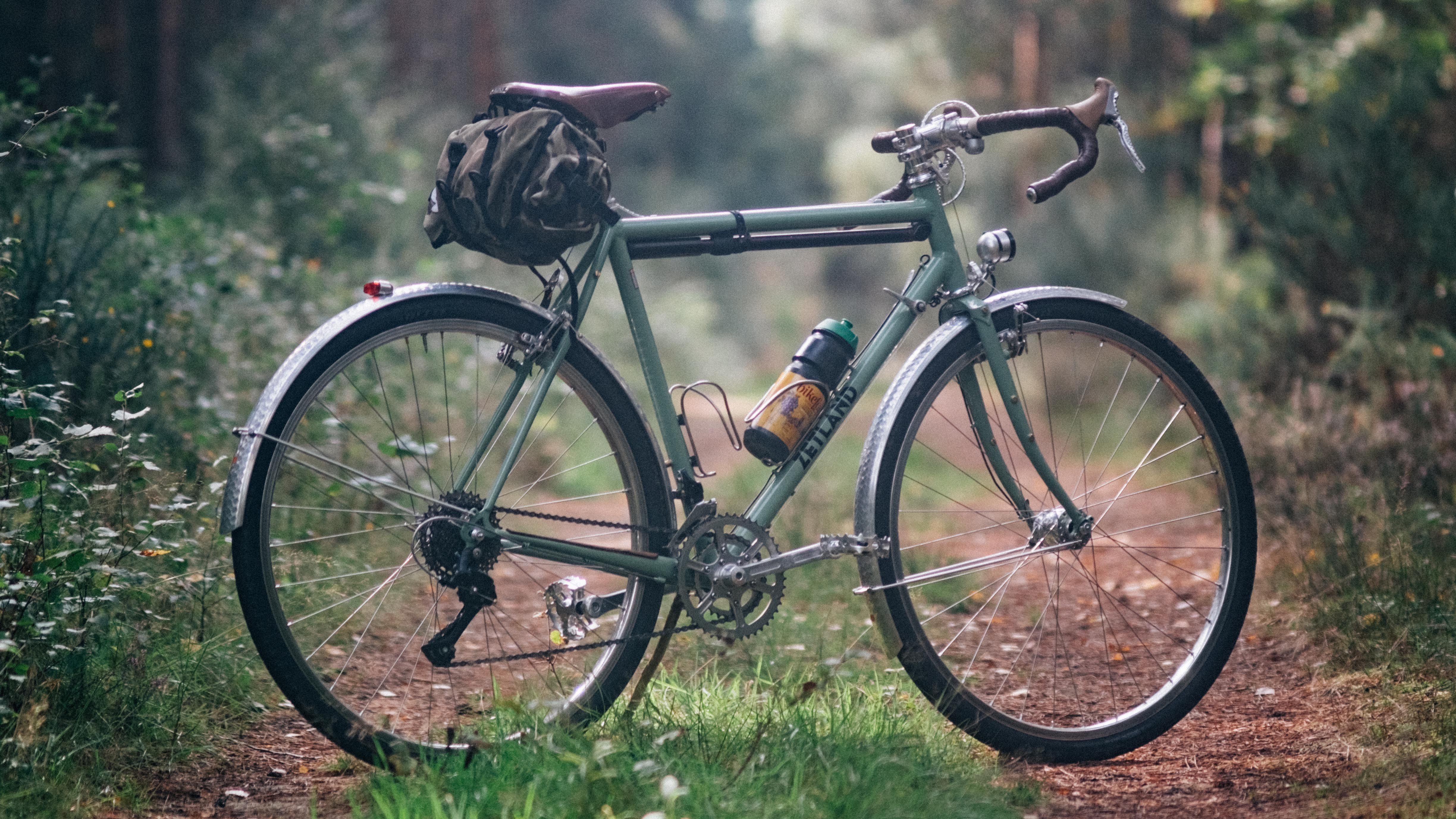 Un vélo de randonnée classique vert sur un chemin boisé