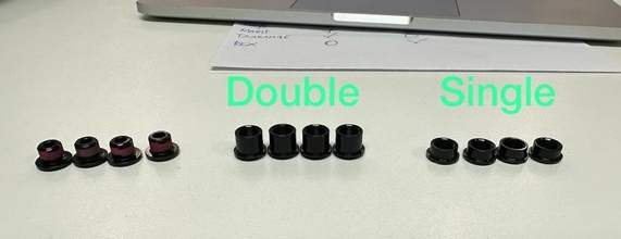 12 boulons de plateau assis sur une table devant un ordinateur portable.  Quatre de chaque dans une taille différente, montrant la différence entre les boulons de plateau simple et double