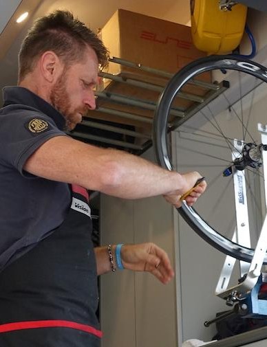 Voici le Moreno Bacchion de Lampre-Merida.  Par une matinée pluvieuse avant le départ de l'étape 2, il était occupé à travailler, gardant son inventaire de roues de course au top.  Il nous a gracieusement laissé le photographier pendant qu'il travaillait.  Ici, il gratte l'excès de colle séchée de la jante à l'aide d'un couteau utilitaire.  Il a également rapidement vérifié que la roue était vraie