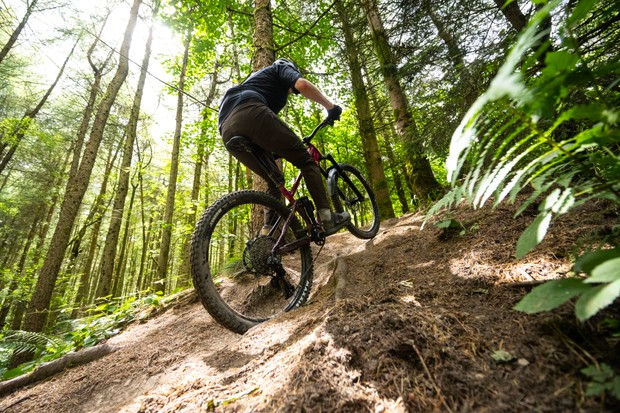 Un vététiste masculin chevauche un marin équipé d'une transmission SRAM GX Eagle et de freins à code en montée lors d'une montée technique