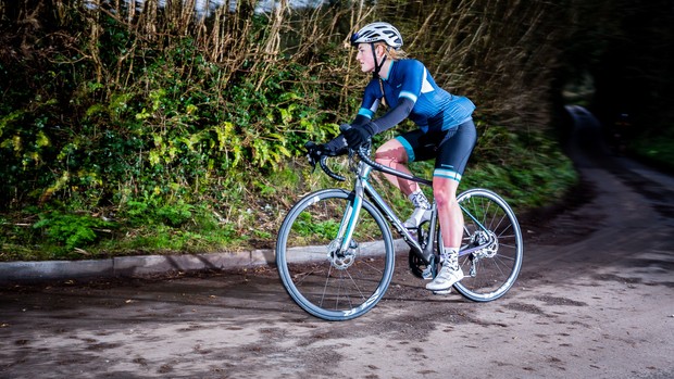 Femme faisant du vélo de route en kit bleu sur un chemin de campagne