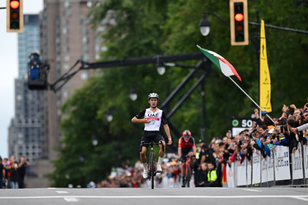 Adam Yates (UAE Team Emirates) points to his team name on his jersey as he celebrates taking victory at Grand Prix Cycliste de Montreal 2023