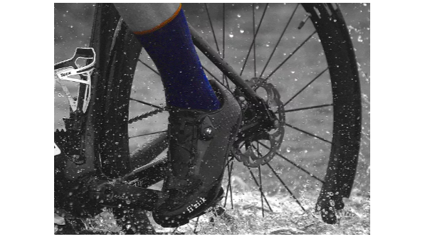 un cycliste traversant une flaque d'eau avec des chaussettes bleues