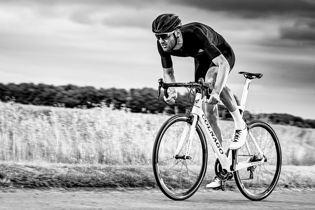 Image en noir et blanc d’un cycliste sur route masculin