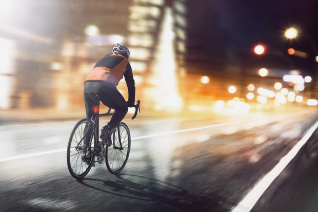 Un cycliste traverse une ville illuminée.