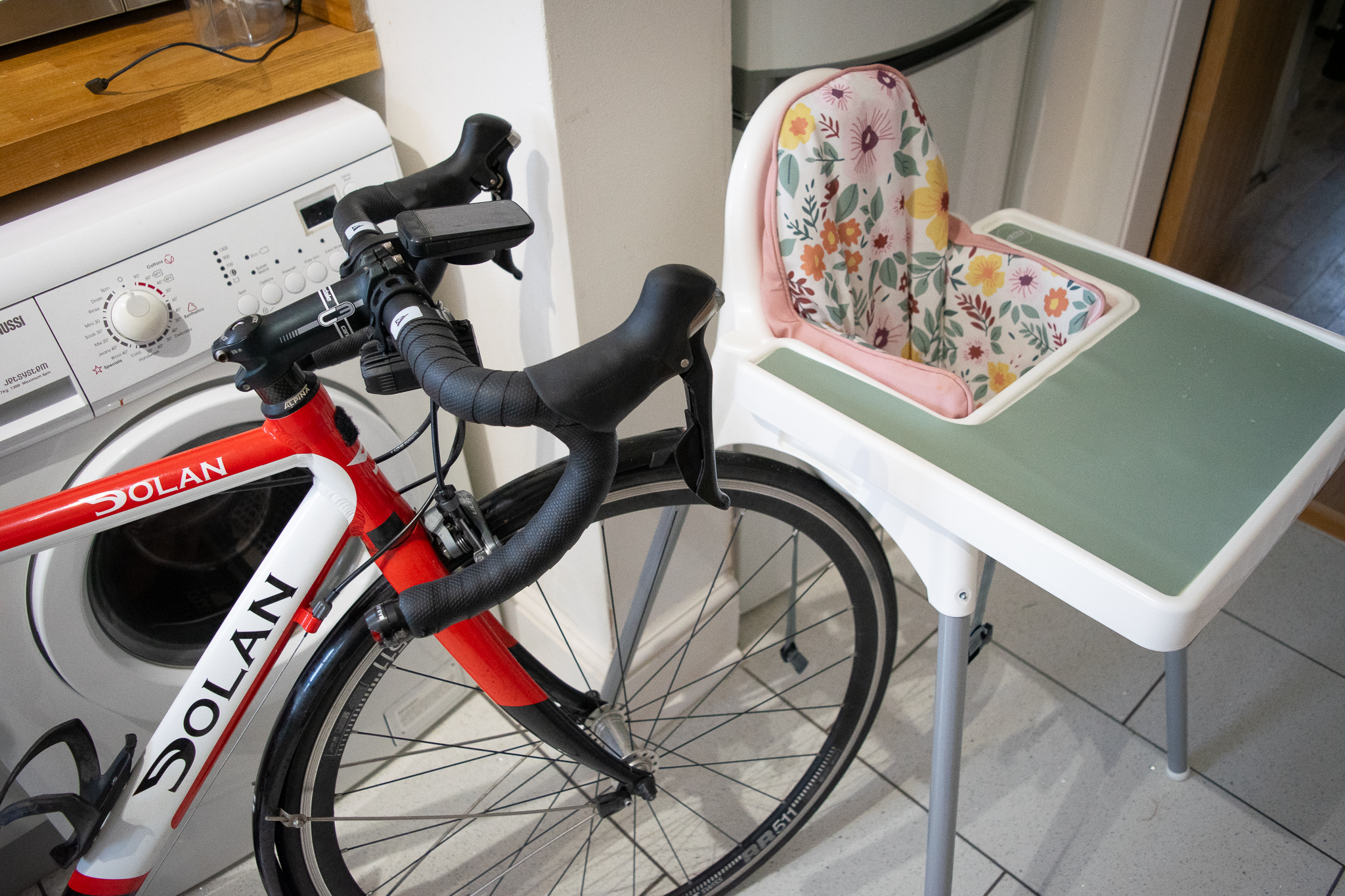 un vélo dans une cuisine près d'une chaise d'alimentation pour bébé