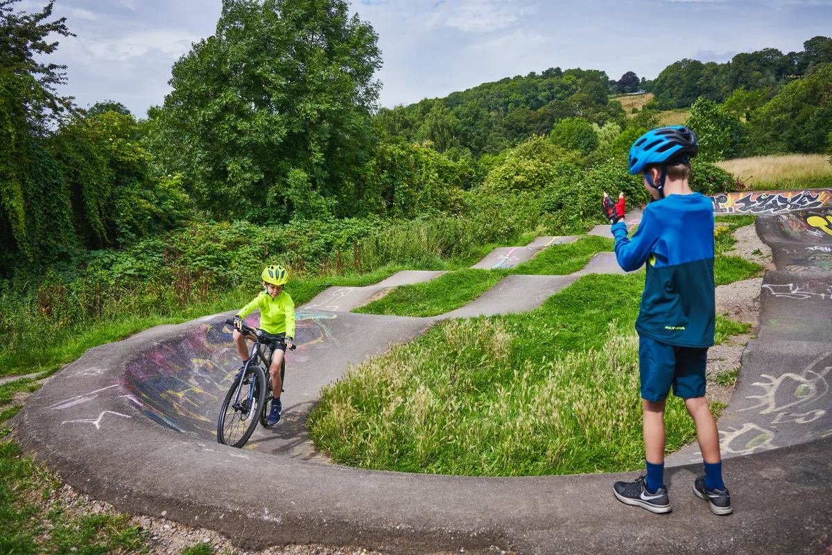 Jeune garçon circulant sur une piste de pompage encouragé par un autre garçon