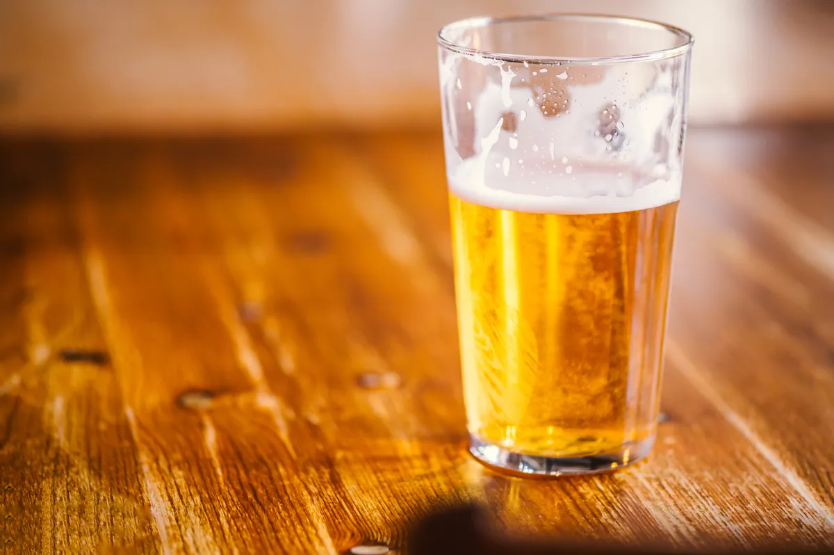 Un verre de cidre de pomme sur une table en bois dans un pub