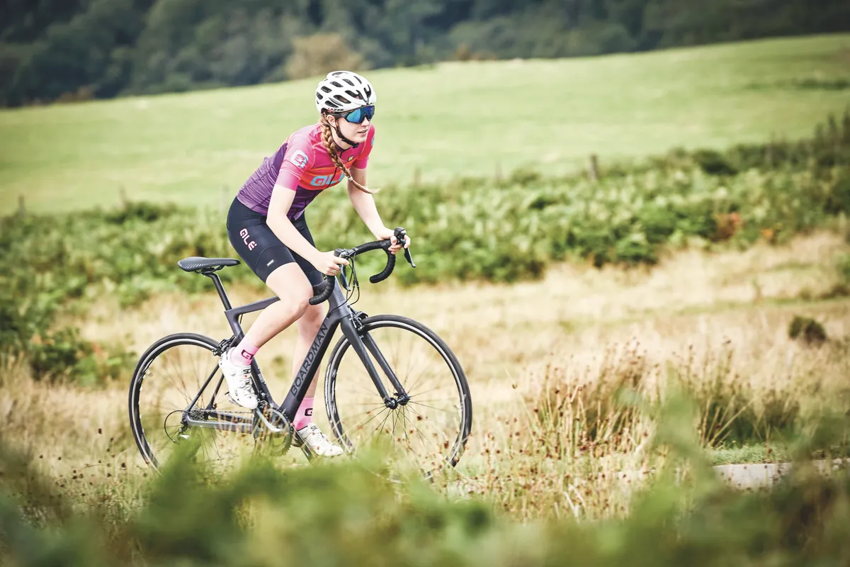 Femme faisant du vélo de route le long de la route.