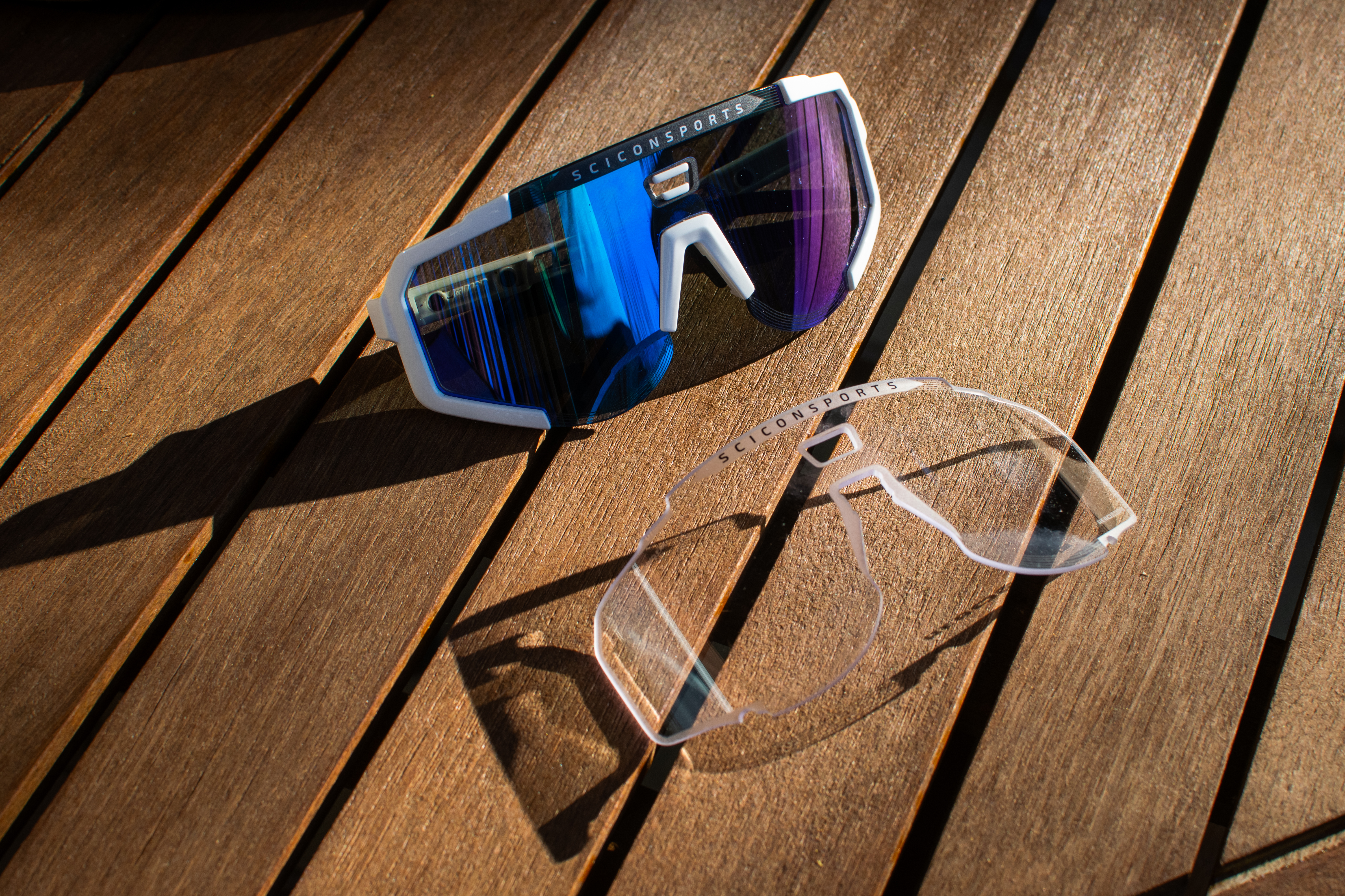 Une paire de lunettes de soleil Scicon Aeroscope et d'objectif clair sur une table en bois