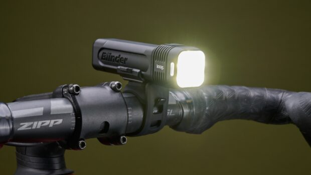 Knog Blinder 1300 front bike light mounted to handlebar on a green background