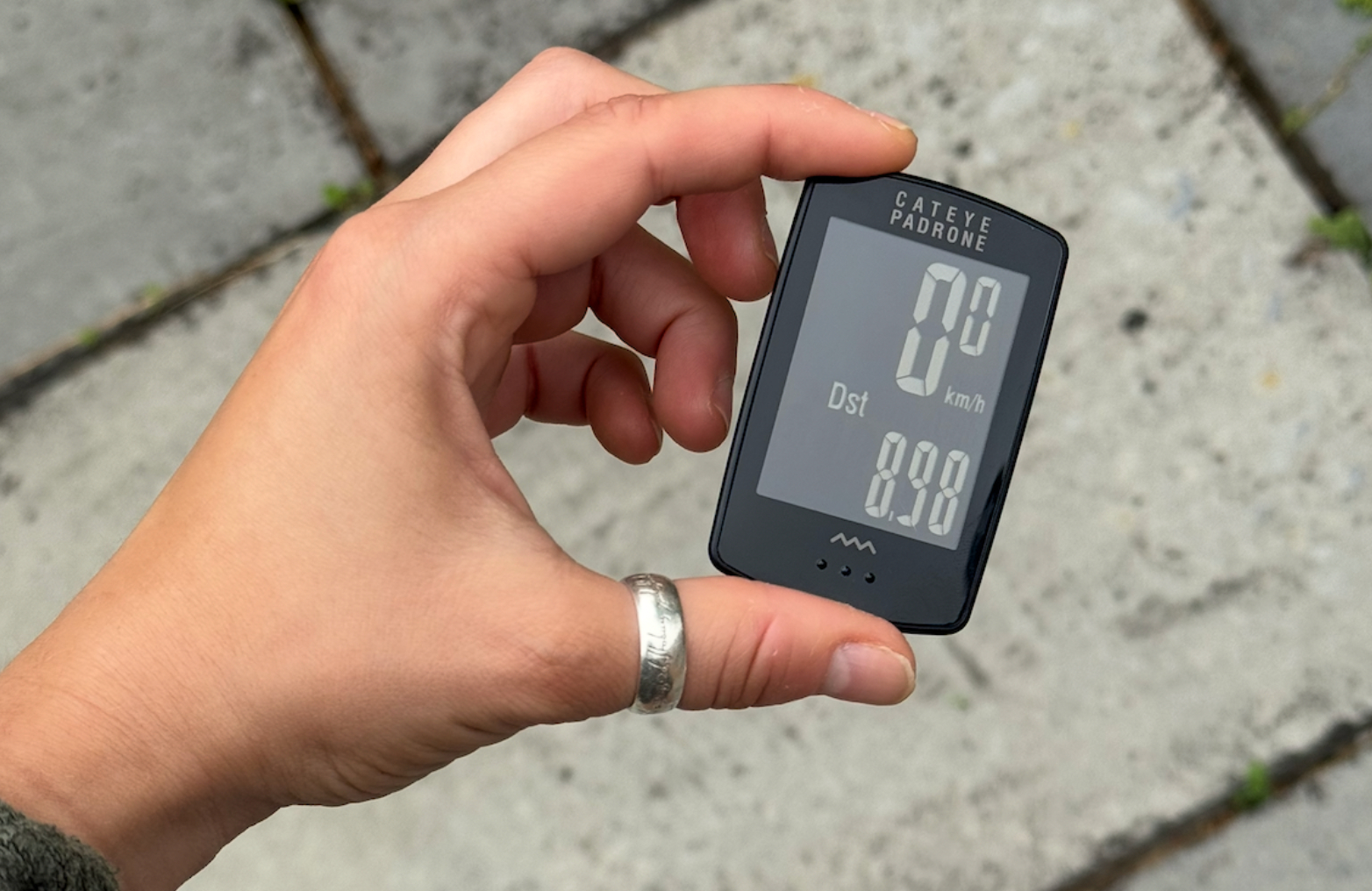 A close up of a small bike computer held in a hand