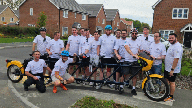 fifteen men stand around a six-person tandem bike