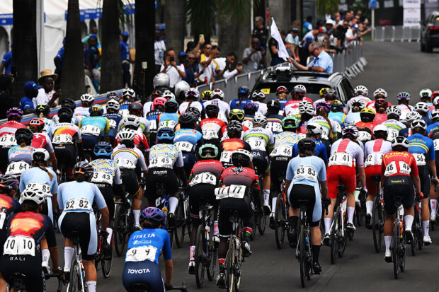 A pack of cyclists ride away from the camera