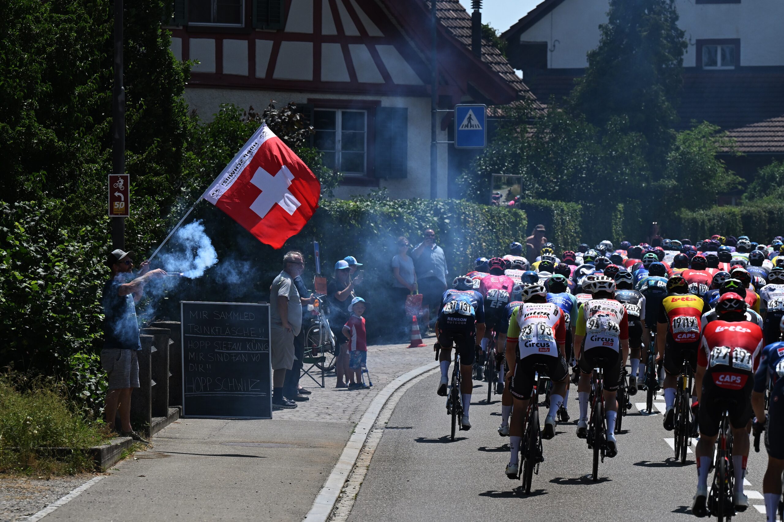 Riders in the Tour de Suisse waved on by a Swiss flag
