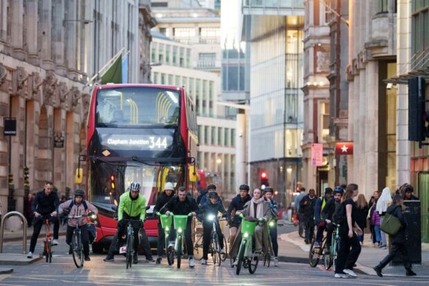 Cyclists in London in front of red bus