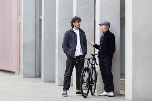 Two men talk with a bike in between them
