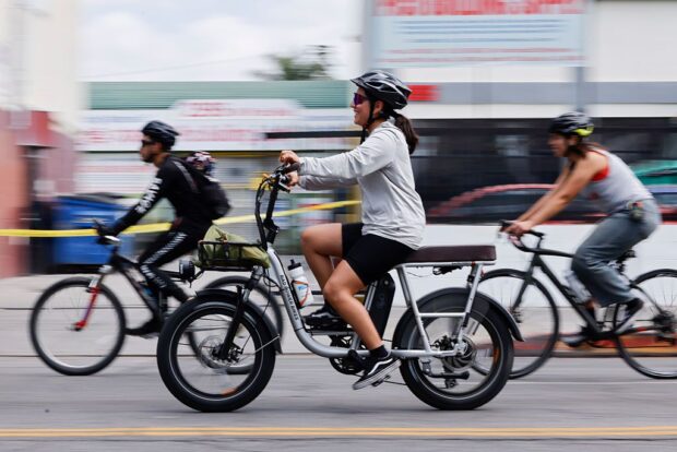 Three people cycling down the road