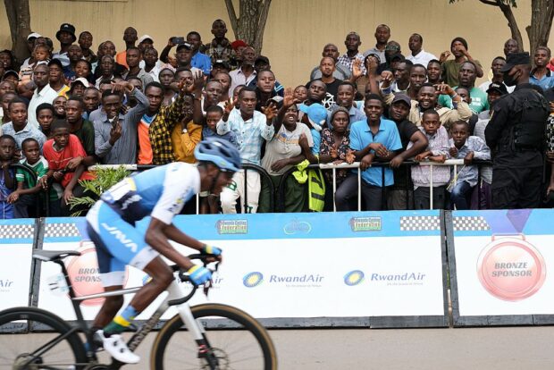 Man cycles next to a crowd of spectators