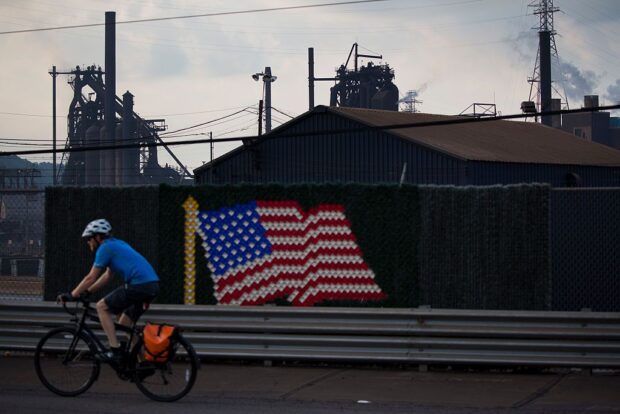 Man cycles past US flag